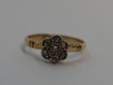 A lady's dress ring having an old cut diamond chip daisy cluster in a pave mount to shaped shoulders