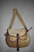 A wicker fishing creel with canvas and leather pouch and canvas top and strap.