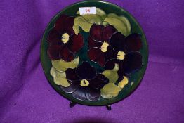 A Moorcroft plate having green ground with hibiscus like floral tube lined pattern,marked