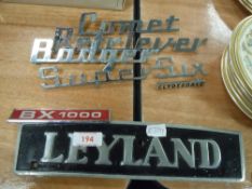 A quantity of vintage car badges and a metal Leyland sign.