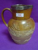A large antique salt glazed jug having HM silver rim decorated with fox hunt and hounds circa 1850
