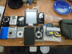 A selection of digital equipment including cameras , Kindle , and Nintendo DS and two Garmin units