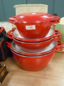 A set of graduated cast and enamel Creuset style casserole pans in red