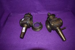 Two Victorian brass carbide lamps having bevelled glass windows and hinged fronts.