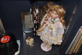 Two dolls with stands, a selection of necklaces and a mirrored photo frame.