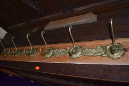 A double set of brass coat rails, mounted on skirting board