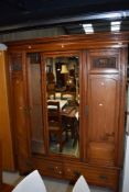 A Victorian mahogany double wardrobe having dentil cornice over mirrored centre panel flanked by