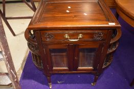 An Oriental hardwood cabinet , having side racks and glazed front, on casters