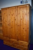 A modern pine triple wardrobe, on drawer base, width approx. 126cm