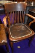 A n early 20th Century stained frame office armchair with leather studded seat