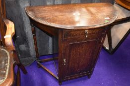 An early 20th Century oak demi lune hall table with cupboard section under, width approx. 76cm