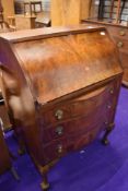 An early 20th Century part walnut/mahogany bureau having serpentine lower section, on ball and