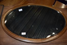 An Edwardian mahogany and inlaid oval wall mirror