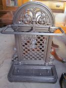 A cast iron umbrella stand with leaf cast decoration and two drip trays