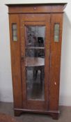 An Edwardian oak wardrobe, the moulded cornice above a mirrored door on bracket feet