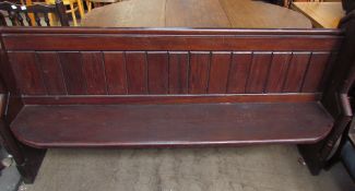 A pine pew, with a panelled back and a solid seat on stiles
