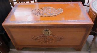 A carved Chinese camphor wood coffer decorated with figures in a landscape on bracket feet