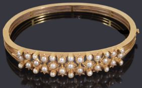 A decorative late Victorian gold seed pearl hinge bangle