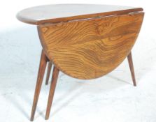 A retro 20th Century Ercol dark beech and elm round coffee table raised on tapering splayed