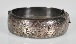 A silver hallmarked bangle having engraved foliate and scroll decorated front with plane back and