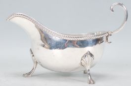 An early 20th century Edwardian Charles and George Asprey silver gravy boat raised on claw feet with
