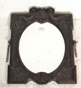 A 19th century Bois Durci mirror having relief cast Art Nouveau scroll works with figural busts of