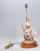 A Capodimonte table lamp in the form of a lady holding a lamb raised on a dark wooden base with a