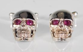 A pair of sterling silver skull and bones cufflinks set with red stone eyes. Stamped sterling. Gross