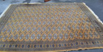 A large 20th century Bokhara rug set with a mustard coloured ground having multiple medallions