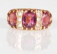 A hallmarked 9ct yellow gold ladies dress ring set with three oval faceted cut purple stones