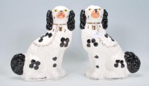 A pair of early 20th Century ceramic Wood and Sons Staffordshire fire dogs having hand painted black