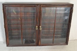 A 20th Century wall mounted mahogany display cabinet of rectangular form having twin glazed doors