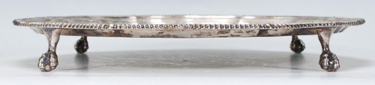 A large silver hallmarked card dish / salver raised on four ball and claw feet, scalloped rim with