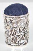 A silver pin cushion of cylindrical form in the Art Nouveau style depicting fairies having a blue