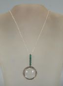 A small silver magnifying glass of round form with the handle set with green stones, on a silver