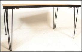 A modernist contemporary metal framed refectory dining table raised on hairpin upright supports in a