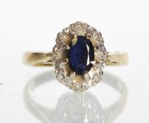 An 18ct gold sapphire and diamond ring. The central oval sapphire 6mm x 4mm within a halo of
