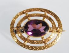 An early 20th century 9ct gold and purple stone brooch. The brooch having a chase decorated