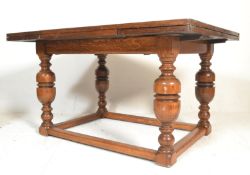 A large early 20th Century oak draw leaf refectory dining table raised on cup and cover supports