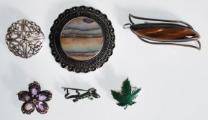 A selection of silver brooches to include a tigers eye brooch in a pierced decoration setting, a