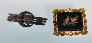 A lat 19th century 14ct yellow gold brooch having a decorative gold scroll boarder around a black