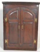 A 19th Century Georgian mahogany hanging corner cabinet twin panelled arched doors opening to reveal