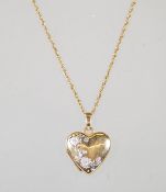 A 9ct yellow gold heart locket pendant having decorative white gold floral decoration on a yellow
