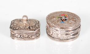 A silver white metal pill box having a hand decorated cockerel atop the hinged lid with repousse