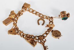 A 9ct gold hallmarked charm bracelet set with ten charms on a curb link chain, charms to include