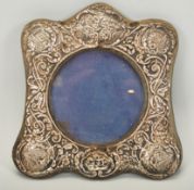 A silver hallmarked rococo easel back picture frame, central circular viewing panel with the frame