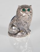 A silver pincushion in the form of a cat set with emerald eyes having a blue velvet pin cushion.
