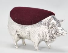 A large silver pin cushion in the form of a pig having a textured detailed body with a purple velvet