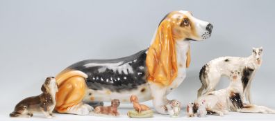A collection of ceramic dog figurines to include a basset hound, two lurcher figurines marked RS,