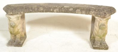 A reconstituted stone garden bench of arched form being raised on armorial lion plinths. Each